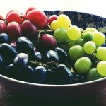 A vibrant bowl of fresh red, green, and black grapes, showcasing healthy eating.