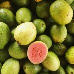 A vibrant display of fresh guavas, highlighting a juicy sliced piece, captured from above.